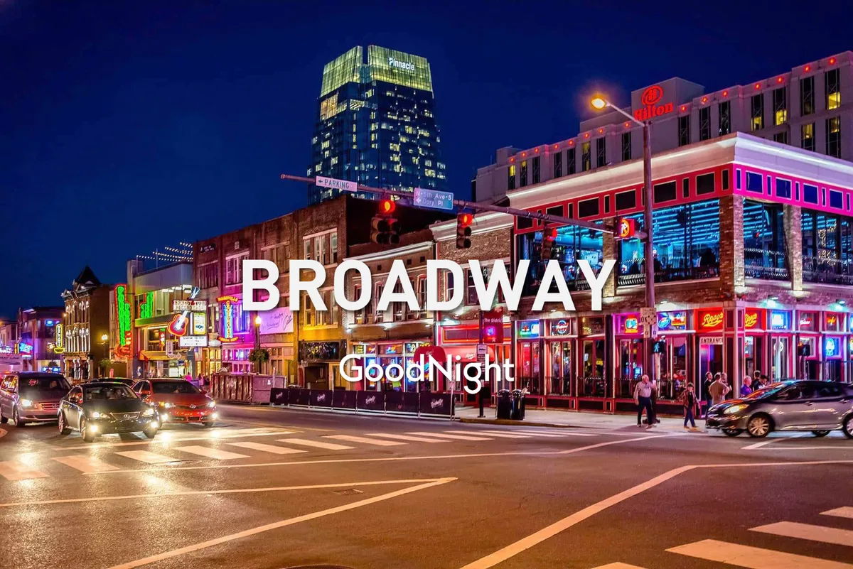 A dynamic evening view of a Midtown street, illuminated by neon signs and bustling with people. The street is alive with energy, as locals and visitors walk among restaurants, bars, and live music venues. Car headlights and vibrant signage capture the nightlife's pulse and excitement.